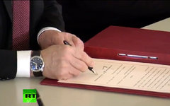 Владимир Путин подписывает договор. Кадр телеканала Russia Today